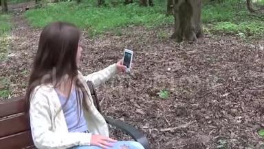 女孩在公园夏天拍自拍照片智能手机。 噗嗤笑了.. 带有稳定<strong>摄像</strong>机的视频拍摄移动<strong>摄像</strong>机